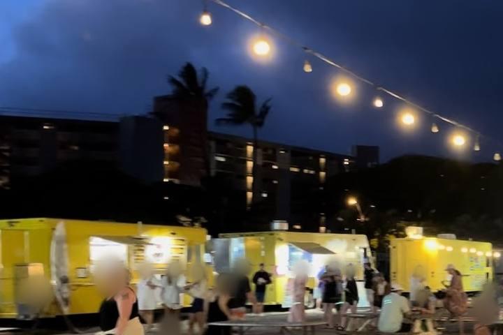 Food trucks and picnic tables under string lights at the Kaanapali truck park